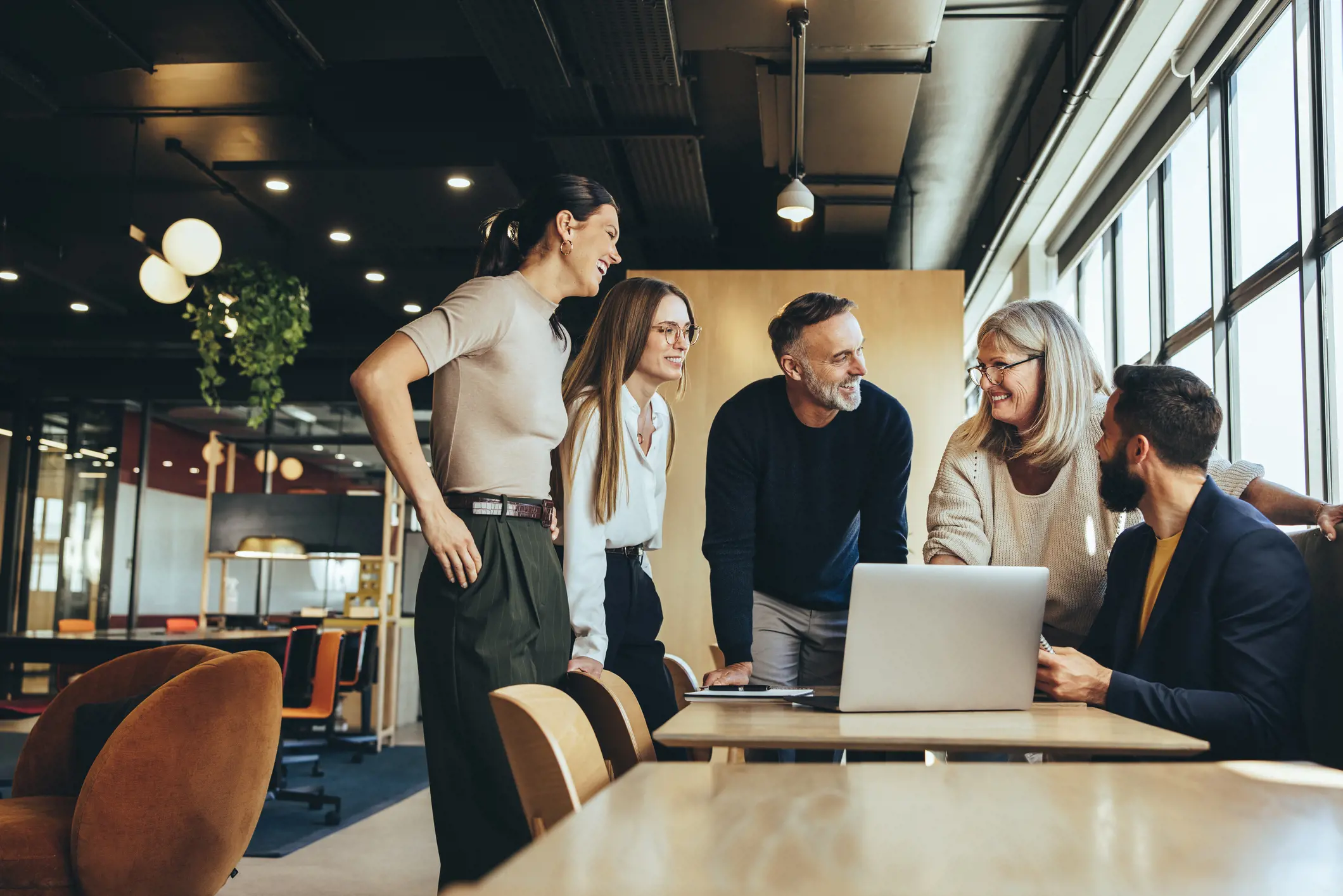Team Meeting Five diverse professionals having a casual meeting around a laptop